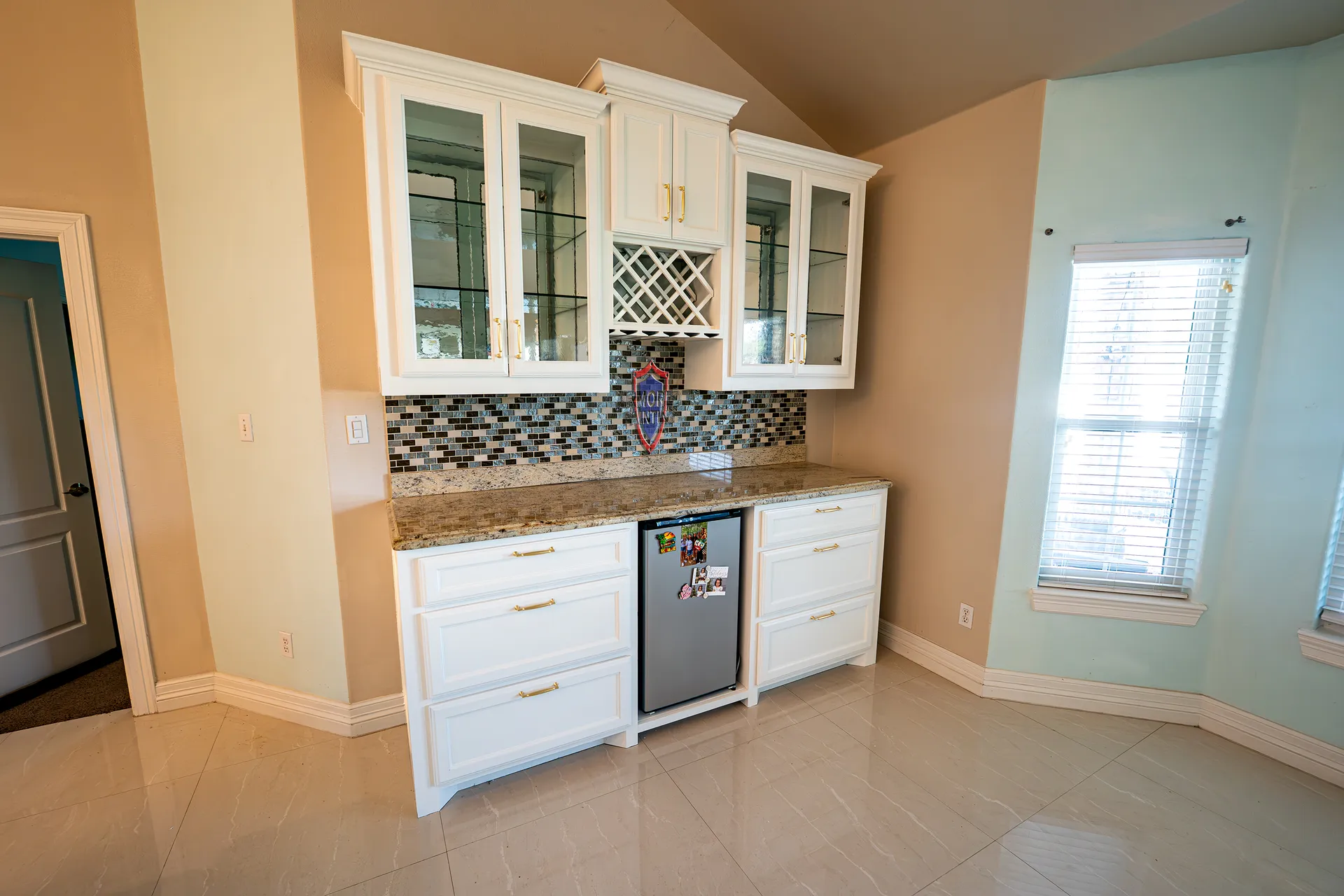 White refinished cabinets with glass fronts and a built-in wine rack