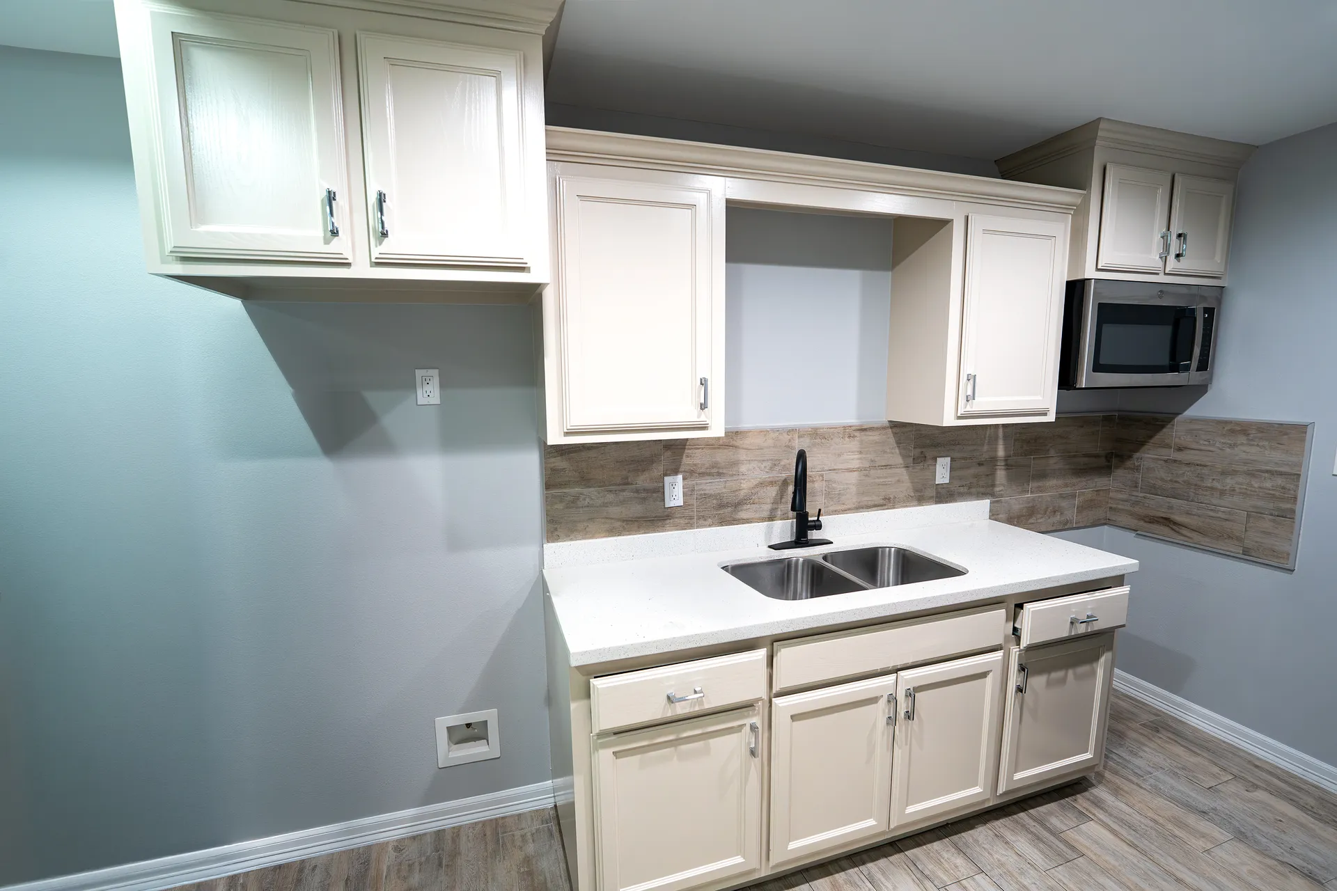 White refinished kitchen cabinets against soft gray walls