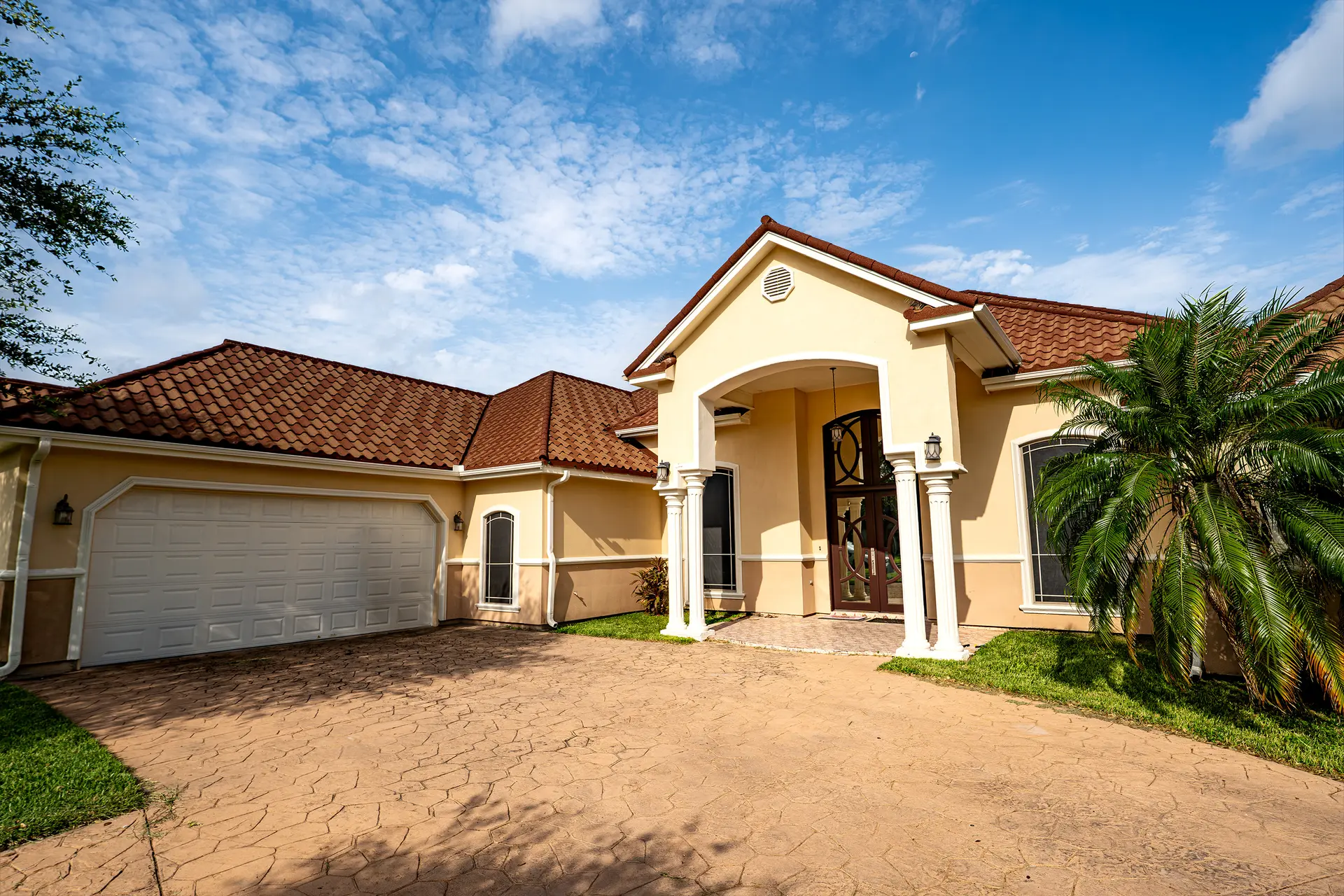 Stucco home with clay tile roof and arched entry after exterior painting