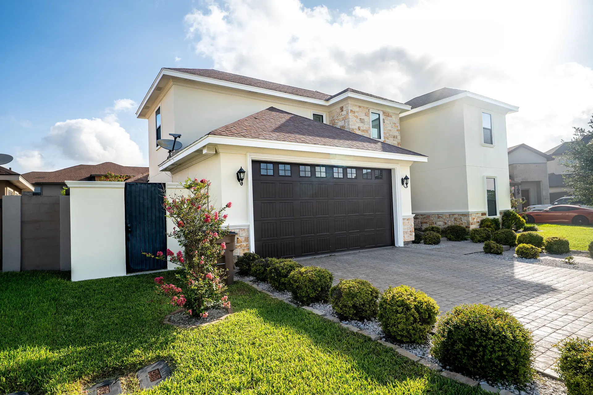 Two-story stucco home with landscaped beds after exterior painting