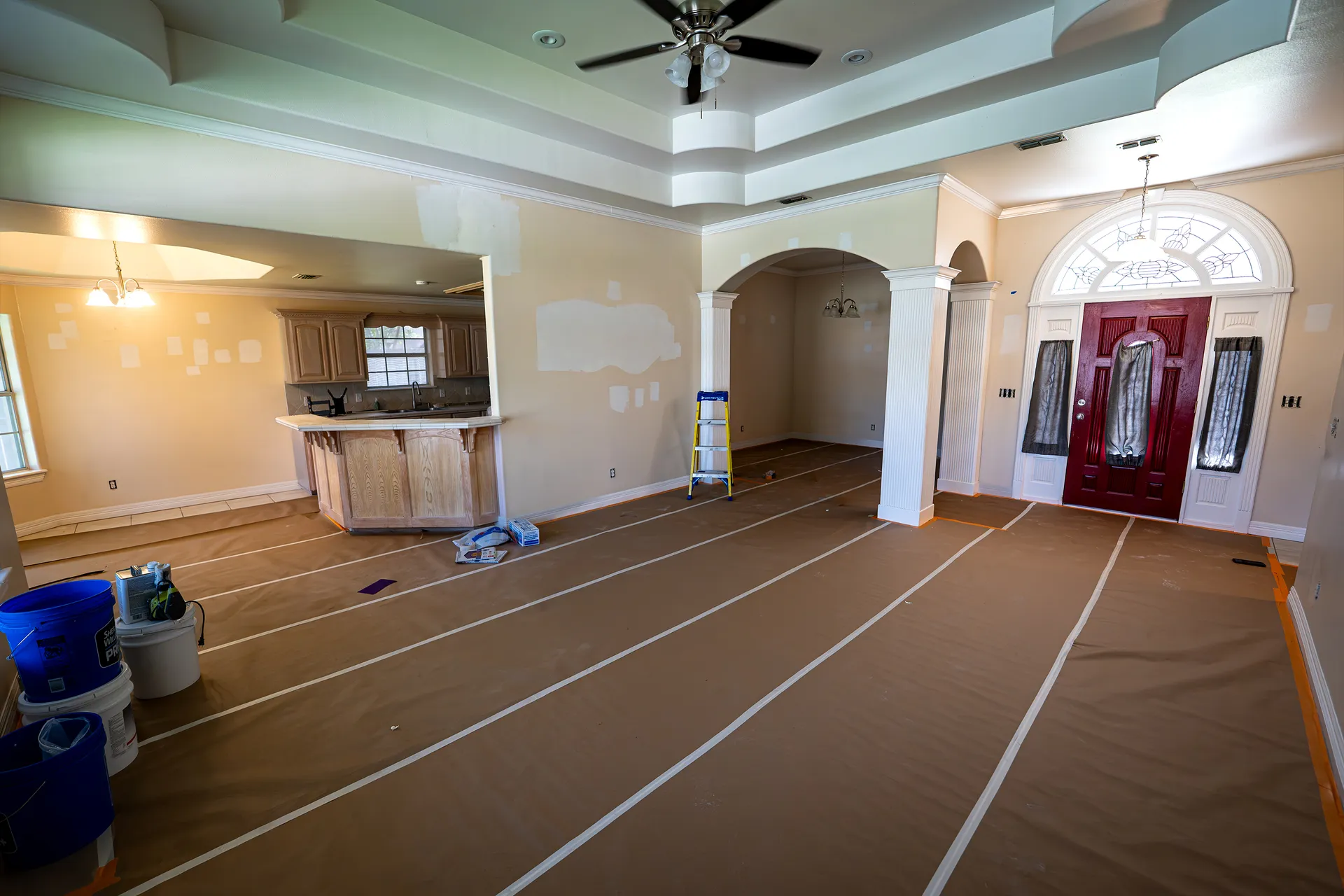 Living room prepped with drop cloths and taped trim before an interior repaint