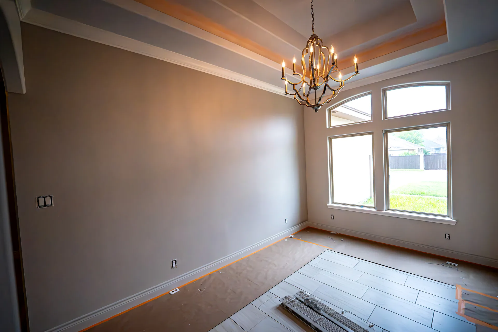 Dining room painted in warm taupe with a chandelier and tray ceiling