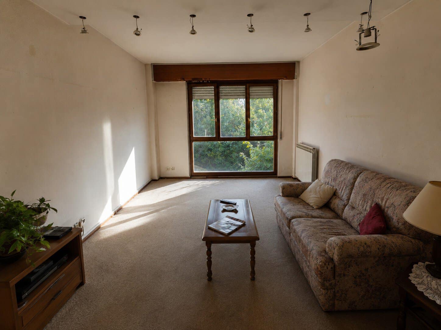 Living room with dated beige walls and worn carpet before repainting