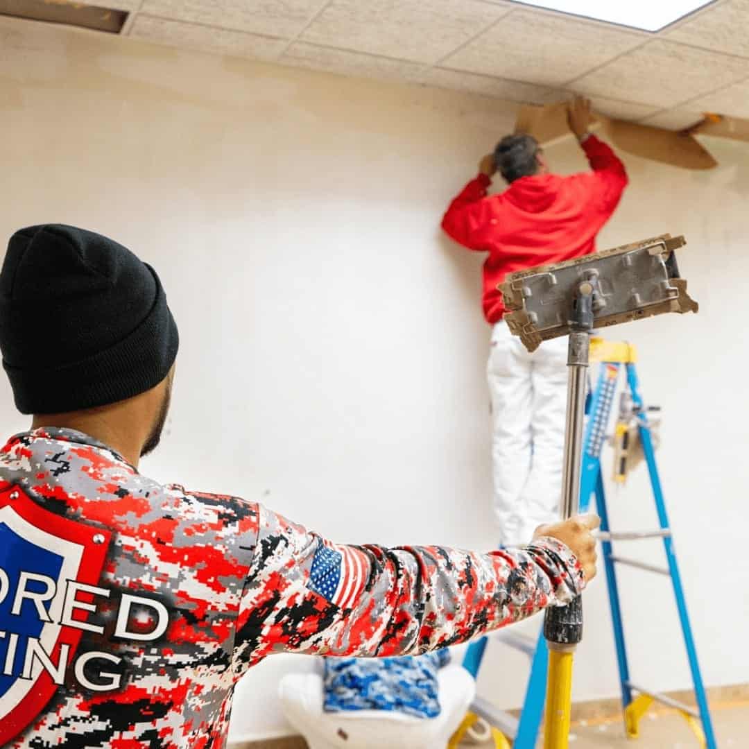 Two Armored Painting crew members painting a commercial interior
