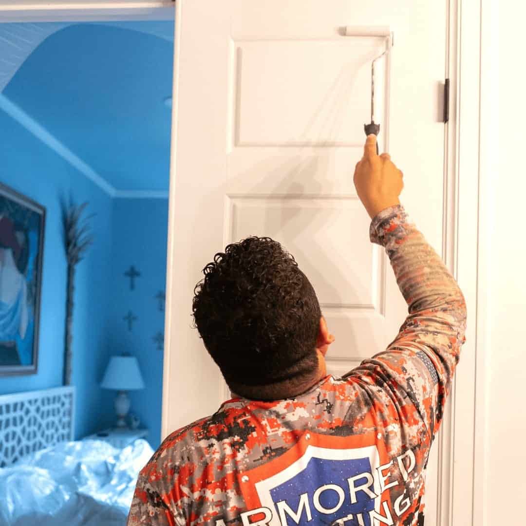 Armored Painting crew member rolling paint onto an interior door