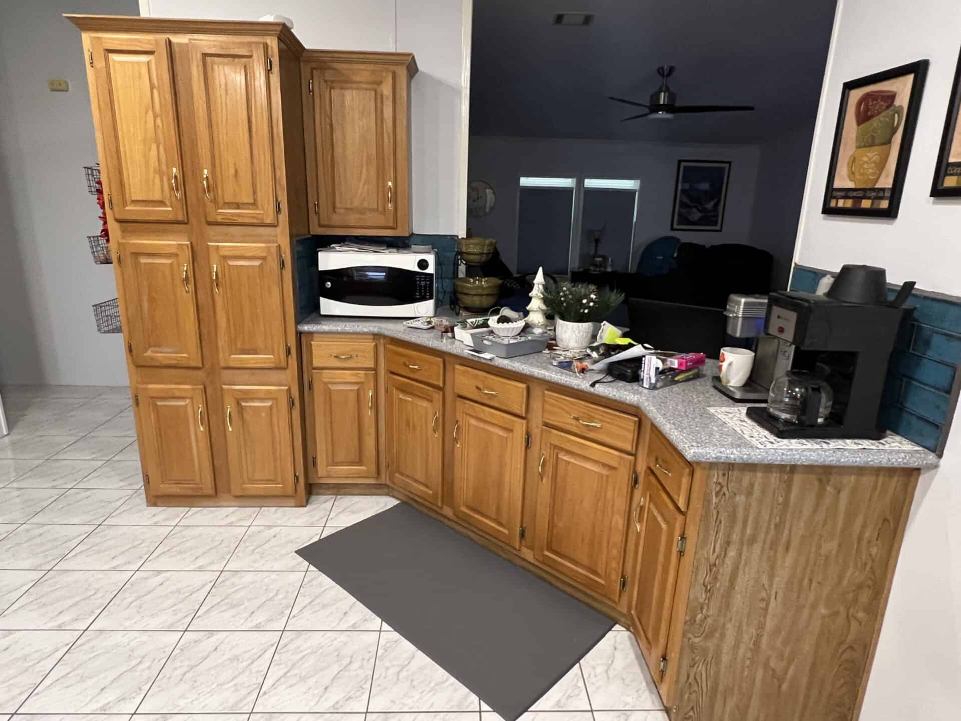 Kitchen scene with wooden cabinets, a microwave, and a coffee maker on a granite countertop. The atmosphere is cozy and organized.