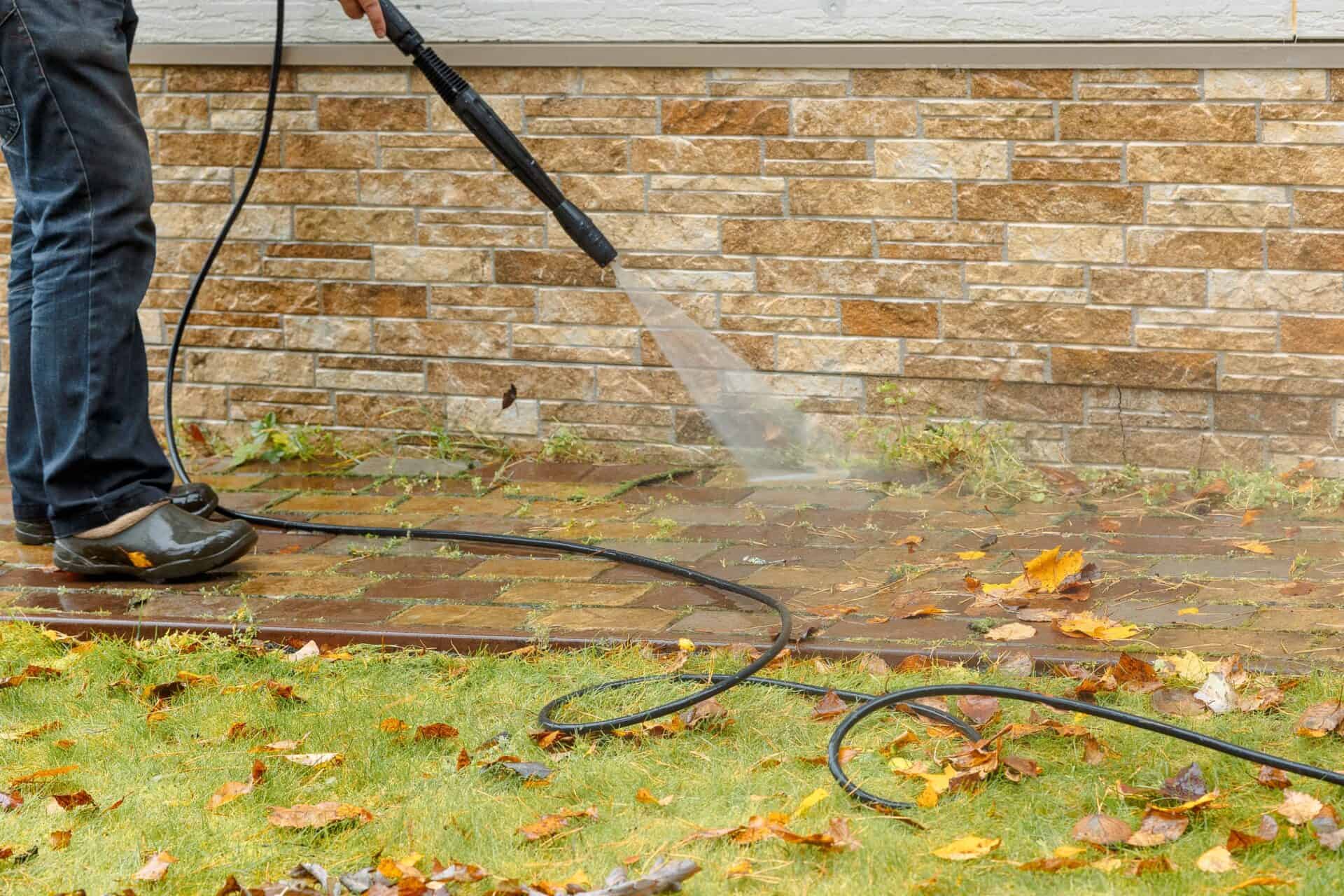man cleaning street with pressure hose